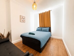A bedroom with a bed, a hanging light fixture, a framed picture, and a window with curtains. - Spacious 3BR Home Near Town • Families, Corporate & Contractors pick • Sleeps 10 (Doncaster)