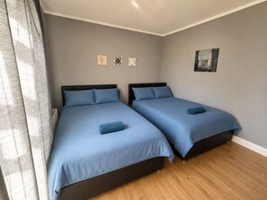 A room with two beds, a radiator, and a framed picture on the wall.