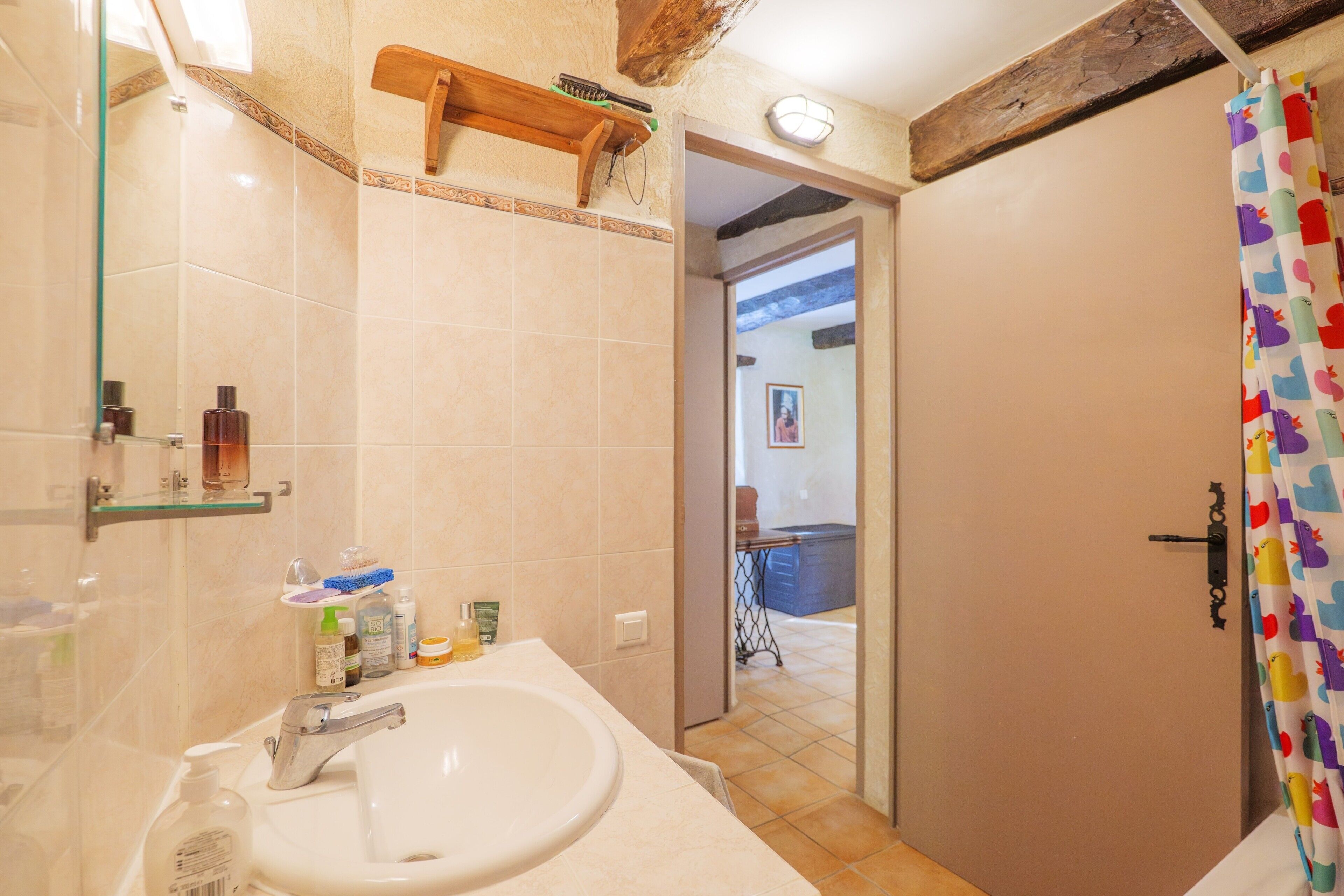 Une salle de bain avec un lavabo, un miroir et un rideau de douche.