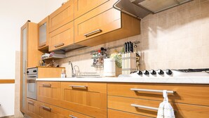 A kitchen with wooden cabinets, a countertop, a stove, and a hanging rack with kitchen utensils. - Apartment 'Tina House' with Balcony, Wi-Fi and Air Conditioning (Florence)