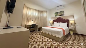 A hotel room with a bed, desk, chair, and a television on a stand. - Caño Tiburones Guest House (Arecibo)