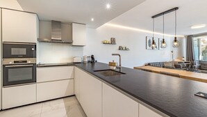 A modern kitchen with a central island, built-in oven, and stainless steel appliances. - Seaview Splendor 2-BR luxury, huge terrace (Fuengirola)