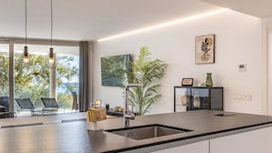A modern kitchen with a large island, stainless steel sink, pendant lights, and a view of the outdoors. - Seaview Splendor 2-BR luxury, huge terrace (Fuengirola)
