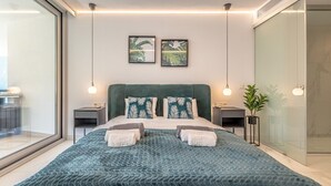 A modern bedroom with a large bed, two nightstands, a large window, and a sliding glass door. - Seaview Splendor 2-BR luxury, huge terrace (Fuengirola)