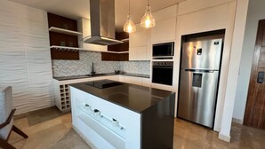 A modern kitchen with a central island, built-in appliances, and pendant lighting.