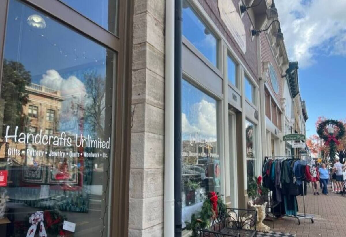 A storefront with a sign reading "Handcrafts Unlimited" offering gifts, pottery, jewelry, quilts, and woodwork.