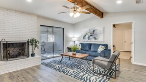 Un salon moderne avec une cheminée, un ventilateur de plafond, un canapé et une table basse.