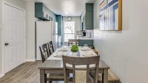 Un coin repas avec une table en bois, dressée pour quatre personnes, et entourée de chaises dotées d’assises rembourrées.
