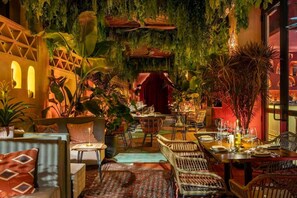 A cozy restaurant with indoor plants, wicker furniture, and a warm ambiance. - Lava Wynwood • Luxury Condo • Free Parking • Rooftop Pool (Miami)