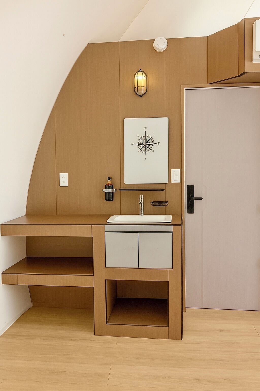 A compact, modern bathroom with a wooden vanity, a sink, and a mirror.