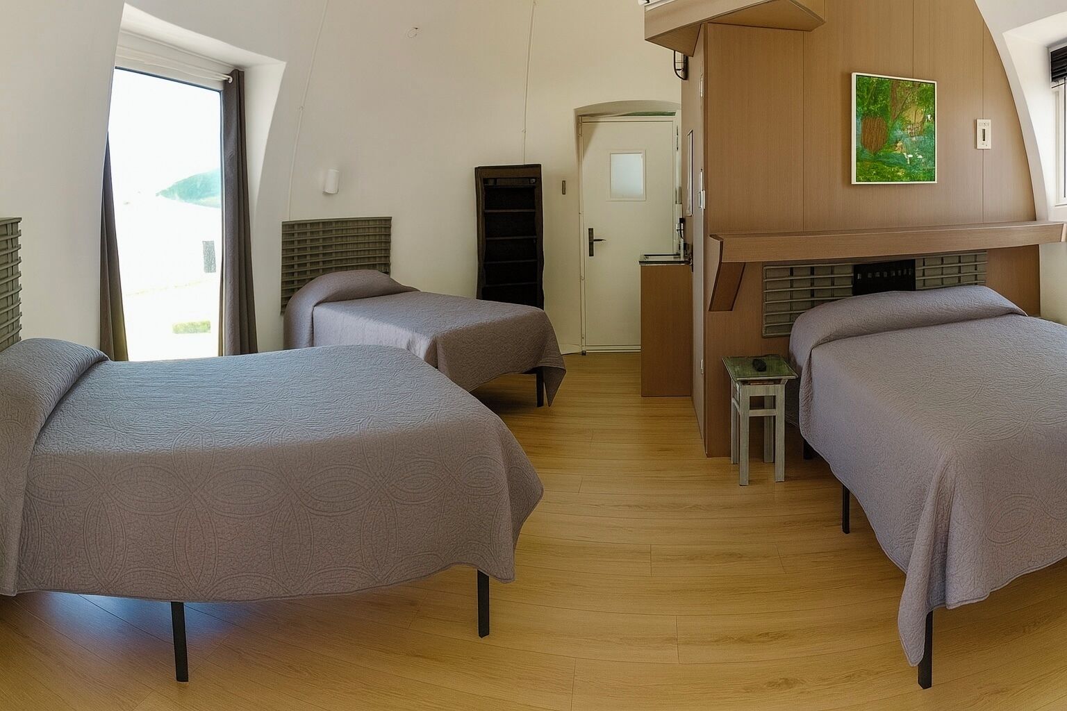 A room with two beds, a small table, a wooden cabinet, and a painting on the wall.