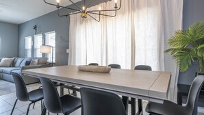 A modern dining area with a long table, black chairs, and a chandelier. - EV_3169 - 4 Bed 3.5 Bath Townhome with Screened-In Private Pool (Kissimmee)