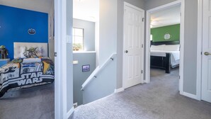 A hallway with a Star Wars-themed bed, a staircase, and a green wall in the adjacent room. - EV_3169 - 4 Bed 3.5 Bath Townhome with Screened-In Private Pool (Kissimmee)