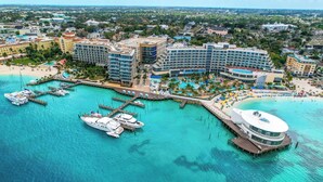 An aerial view of a resort with multiple buildings, a marina with yachts, and a beach area.