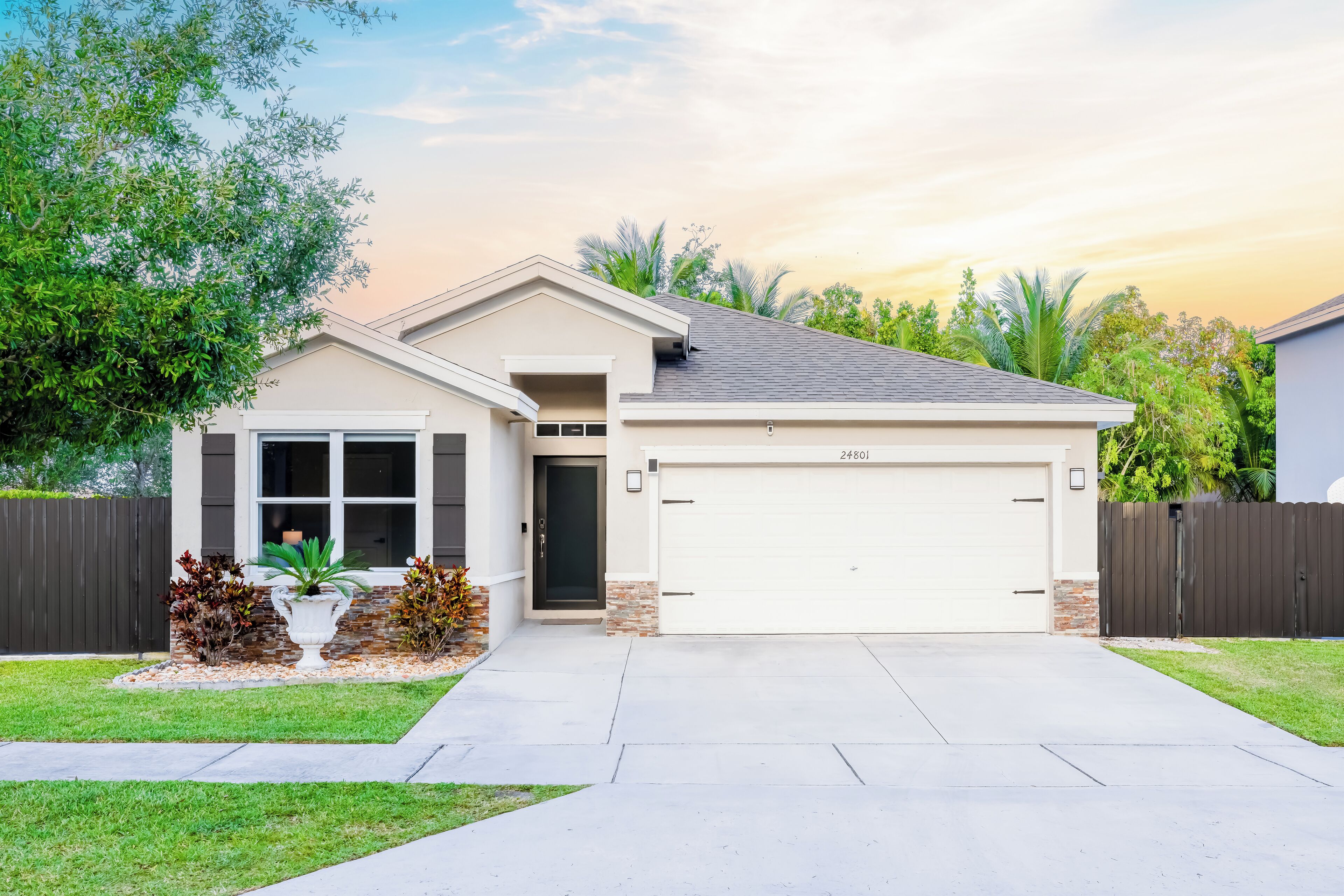 A residential house with a garage, a front porch, and a well-maintained lawn.