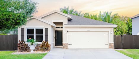 A residential house with a garage, a front porch, and a well-maintained lawn.