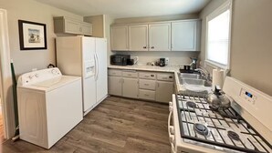 A compact kitchen with a refrigerator, microwave, stove, and sink. - The Pedal Pad - 3 BED / 1 BATH @ central location (Wichita Falls)