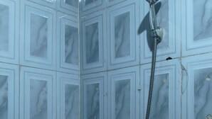 A shower with a handheld showerhead and a wall-mounted faucet. - Oasis Place (Port Harcourt)