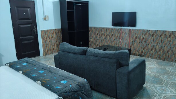 A room with a bed, a sofa, a TV, and a wardrobe. - Oasis Place (Port Harcourt)