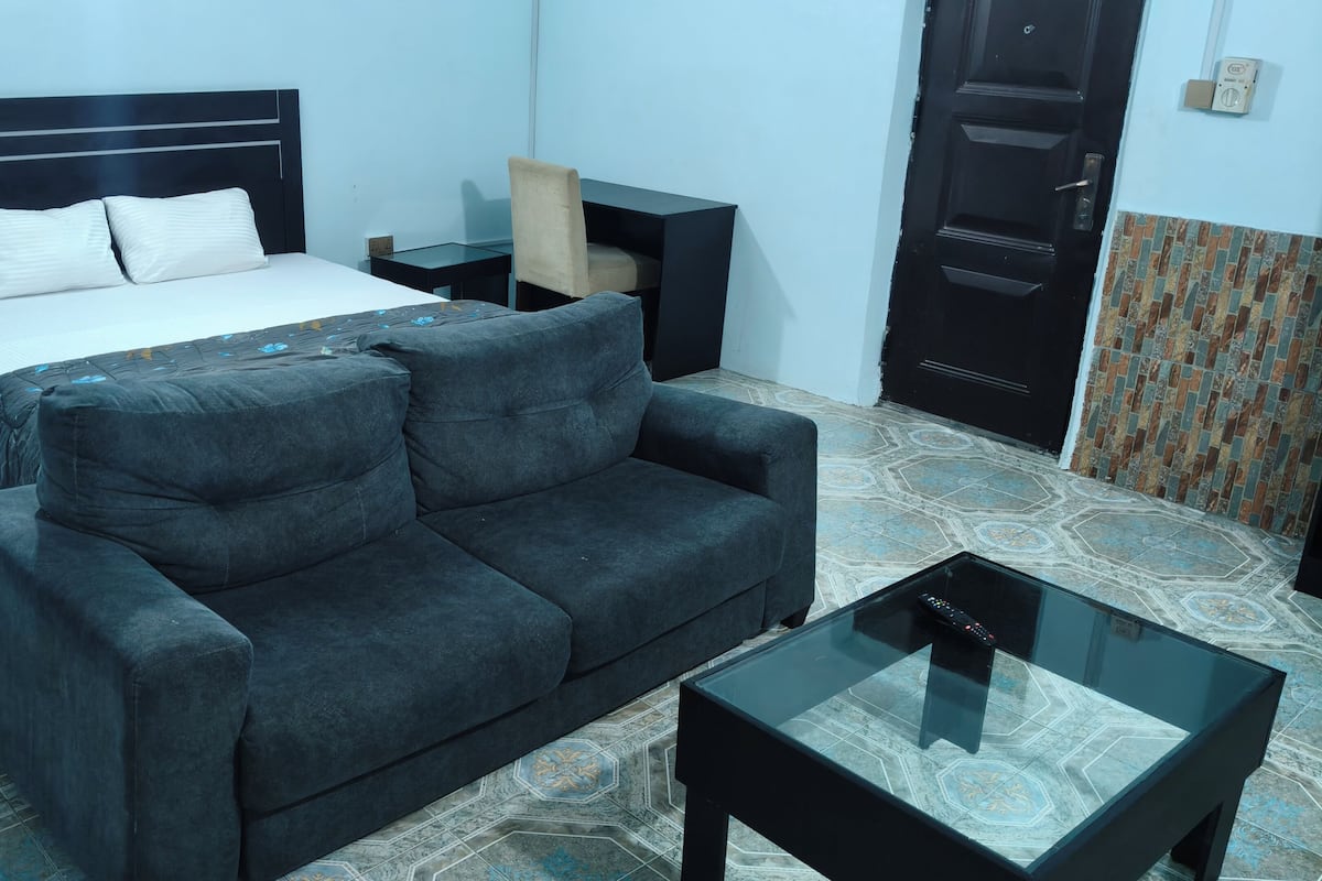 Una habitación con una cama, un sofá, una pequeña mesa y una puerta.