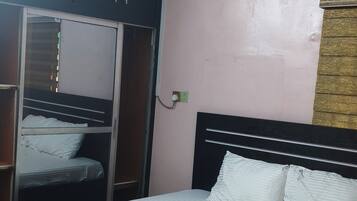 A bedroom with a bed, a ceiling fan, a wardrobe, and an air conditioning unit.