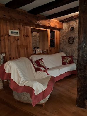 A wooden interior with a sofa, a clock, and a wall-mounted compass.