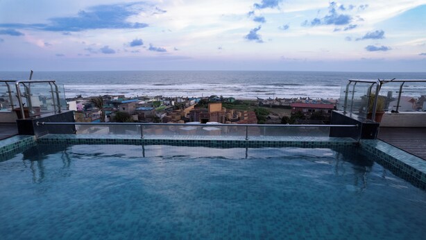A swimming pool with a view of the ocean and a town in the background.