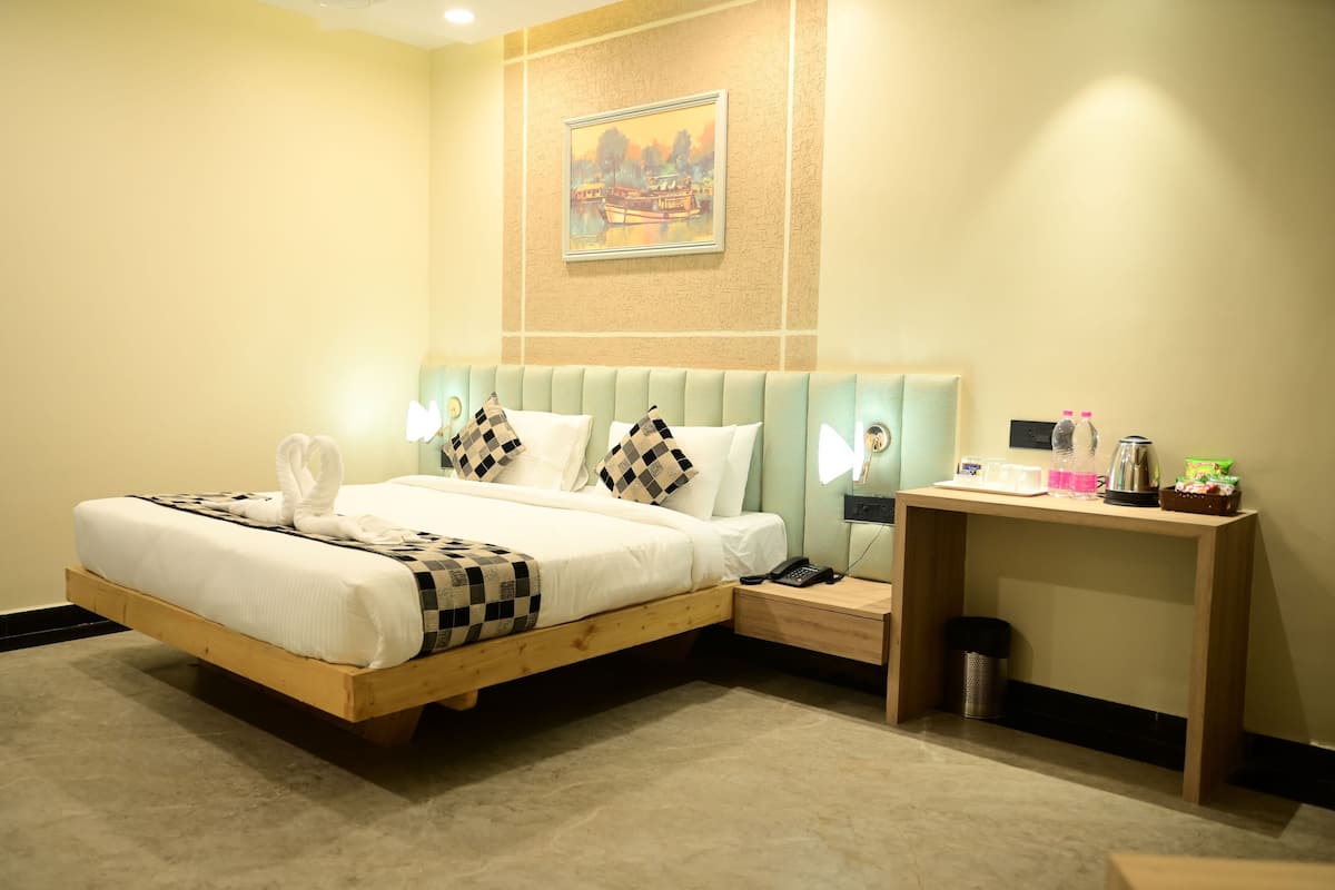 A hotel room with a wooden bed, a nightstand, a desk, and a painting on the wall.