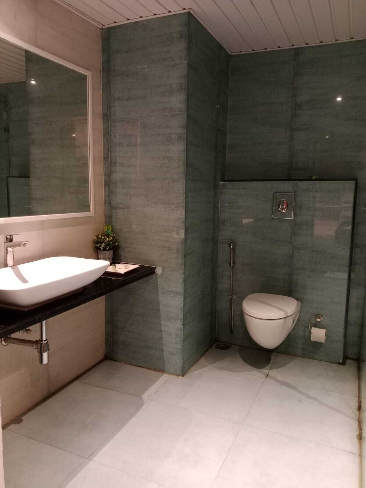Une salle de bain avec un lavabo blanc, un miroir, des toilettes et une douche.