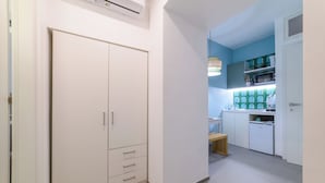 Une cuisine moderne avec des meubles blancs, un petit réfrigérateur et un tabouret en bois.