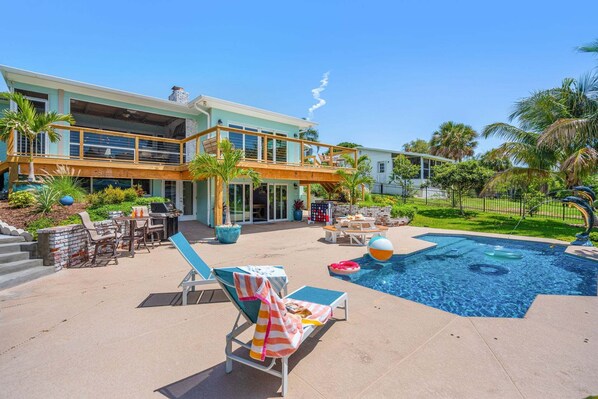 A two-story house with a swimming pool, outdoor seating, and a fenced garden area.