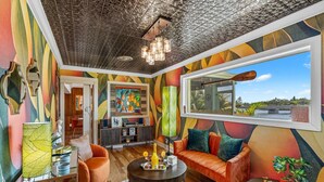 A vibrant living room with a large window, a fireplace, and a colorful abstract mural. - Mango Shores (Melbourne)