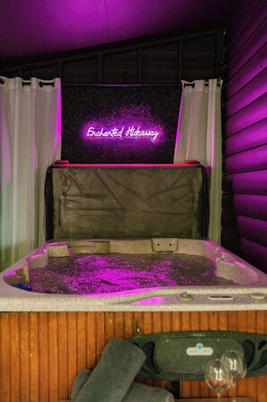 Un jacuzzi con un letrero de neón que dice "Enchanted Stinkaway" y una pared de madera al fondo.