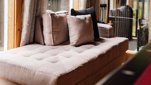 A sofa with cushions in a room with large windows and curtains.