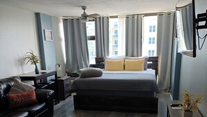 Un dormitorio moderno con una cama grande, un sofá de cuero oscuro y una pequeña mesa con un florero.