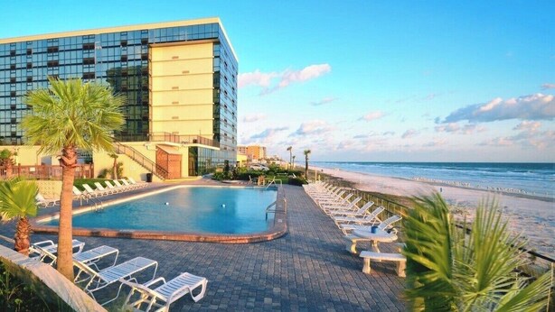Un hotel moderno con piscina, acceso a la playa y vista al océano.