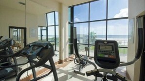 Un gimnasio con equipo de ejercicio y amplias ventanas que ofrecen vistas al exterior.