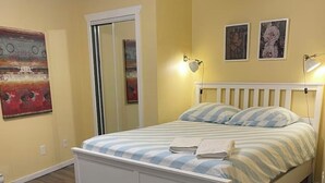 Ein Schlafzimmer mit einem Bett, Holzboden, einem weißen Kopfteil und zwei Wandlampen.