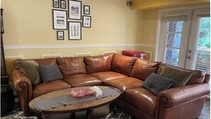 Ein braunes, ledernes Ecksofa mit einem runden Couchtisch, einem gemusterten Teppich und gerahmten Bildern an der Wand.
