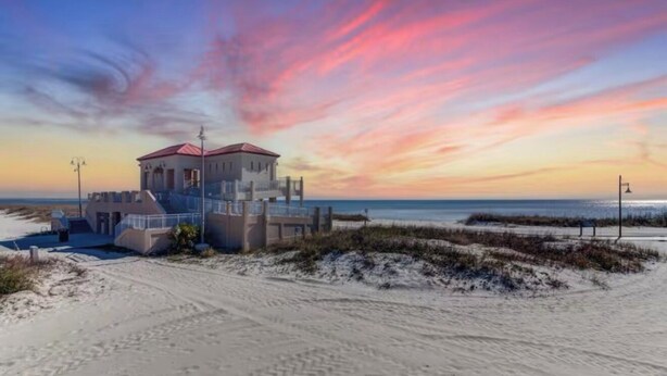 A beachside building with a red roof, a staircase leading to the entrance, and a view of the ocean. - Recently Updated Trendy Biloxi Beach Condo (Biloxi)