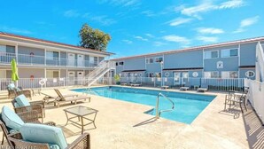 A pool area with lounge chairs and a staircase leading to an upper level. - Recently Updated Trendy Biloxi Beach Condo (Biloxi)