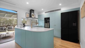 Eine moderne Küche mit einer zentralen Kochinsel, einem schwarzen Kühlschrank und hellblauen Schränken.