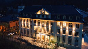 A large, multi-story building with a symmetrical facade, prominent central entrance, and a steeply pitched roof. - H24 Parkhotel Thale (Thale)