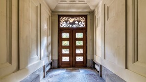 A hallway with a blue carpet, a wooden door with glass panels, and a decorative metal grille. - H24 Parkhotel Thale (Thale)