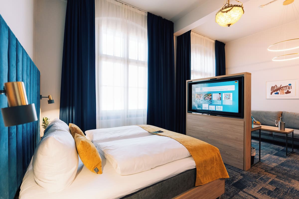 A hotel room with a bed, a TV, a sofa, and a coffee table.