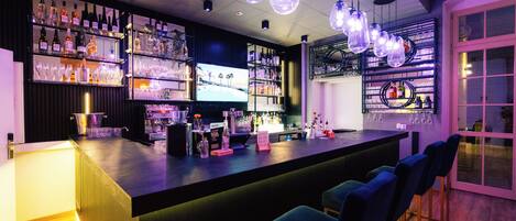 Una zona de bar con estantes llenos de botellas, vasos y una pantalla de televisión.