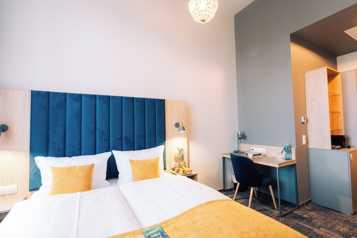 A hotel room with a bed, desk, and kitchenette.