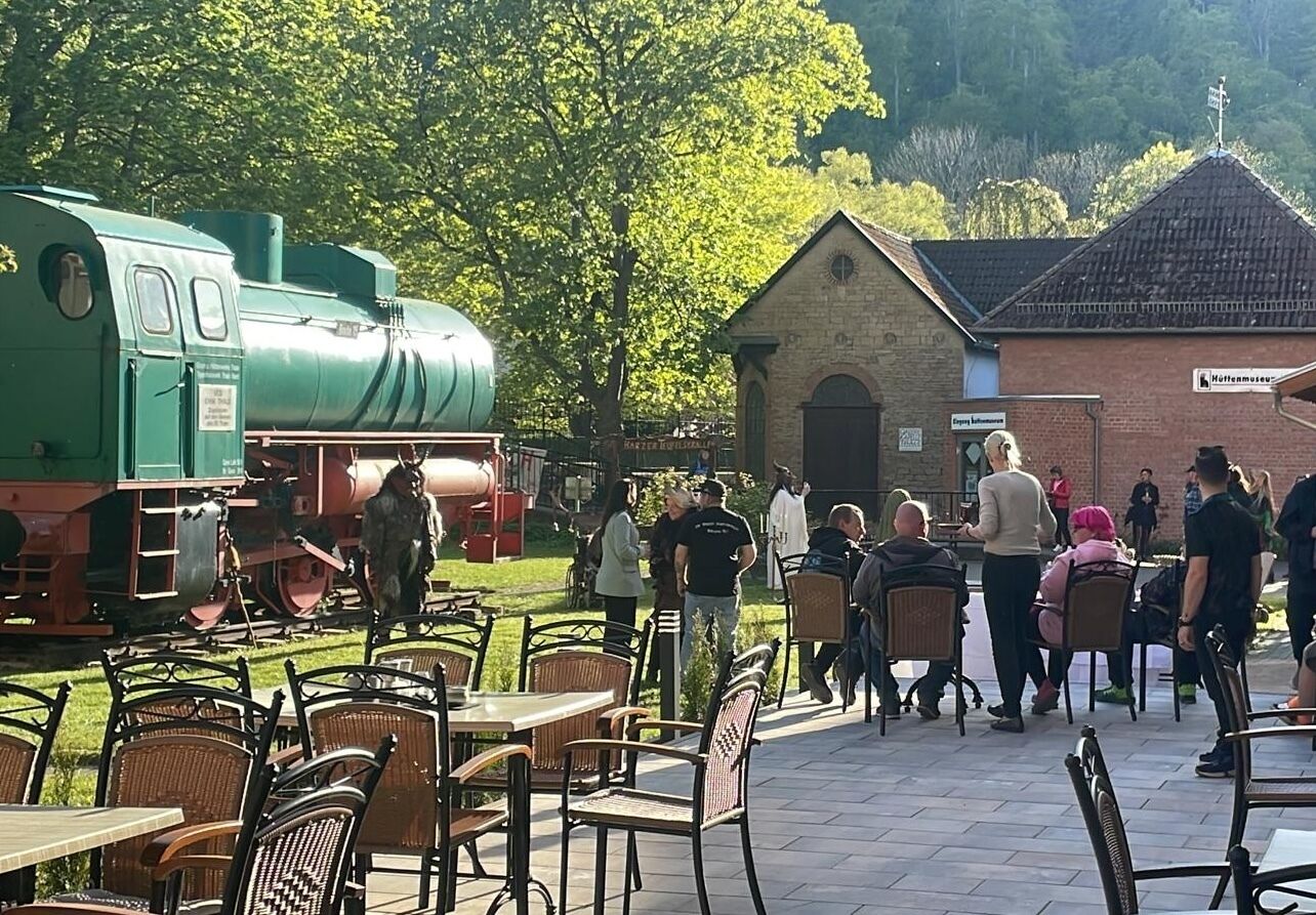 Una locomotora de vapor verde frente a un edificio con un cartel que dice 'Hotelmuseum'.