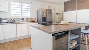 Een moderne keuken met witte kasten, een roestvrijstalen koelkast, een vaatwasser en een houten aanrecht.