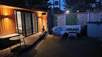 A cozy outdoor patio with a wooden deck, a cushioned seating area, and a table.